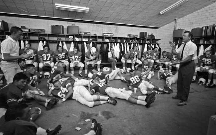 Texas coach Darrell Royal talking to team in locker room after game vs Oklahoma at Cotton Bowl Stadium.